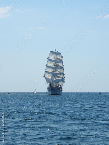 A sailing ship with white sails on three masts at sea. The concept of a cruise, vacation at sea, sailing, yachting.