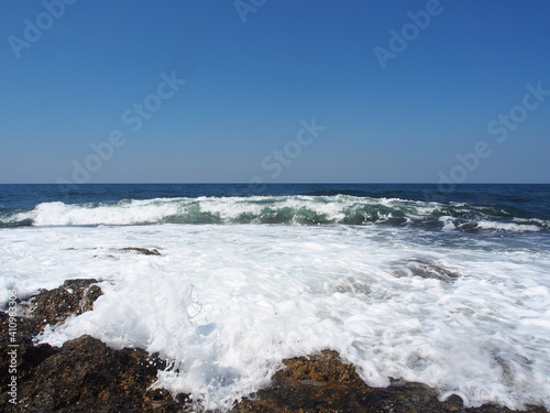 Fototapeta Naklejka Na Ścianę i Meble -  The sea wave runs on the shore. A foamy sea wave rolls over the rocky shore, close-up, seascape.