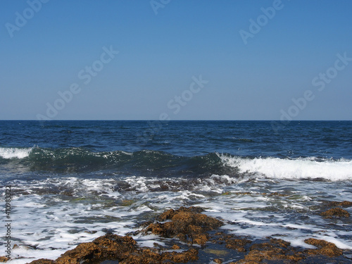 Fototapeta Naklejka Na Ścianę i Meble -  The sea wave runs on the shore. A foamy sea wave rolls over the rocky shore, close-up, seascape.