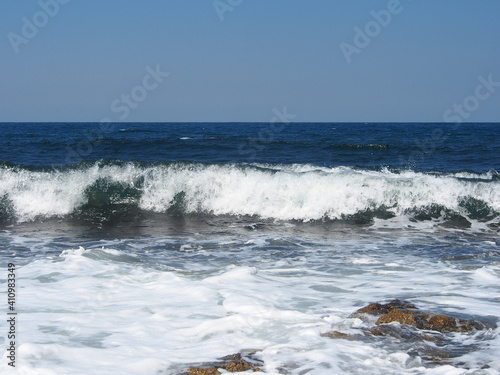The sea wave runs on the shore. A foamy sea wave rolls over the rocky shore, close-up, seascape.