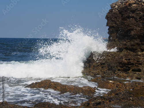 Fototapeta Naklejka Na Ścianę i Meble -  The sea wave runs on the shore. A foamy sea wave rolls over the rocky shore, close-up, seascape.