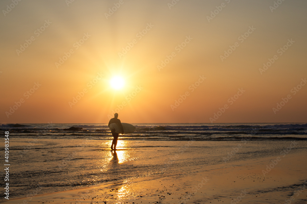 surfer at sunset with sunburst porthtowan cornwall England uk 