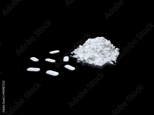Cocaine drug powder and pills on black background