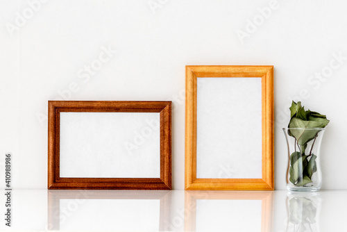 Two wooden frames with a white insert inside and a green one with a glass. Photo frame on a white wall background.