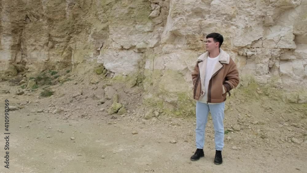 A young guy in a jacket and jeans pose an abandoned stone carier A young guy in a jacket and jeans pose an abandoned stone carier