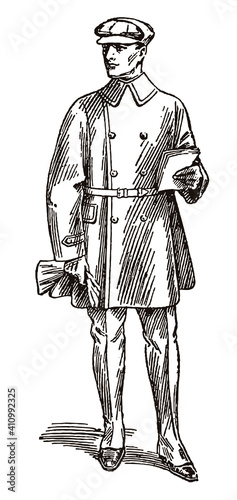 Standing biker from the early 20th century in antique motorcycle clothing, wearing double-breasted jacket, leggings, cap and gloves, holding some papers