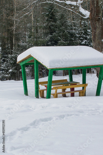 Green-painted wooden gazebo in the winter forest.