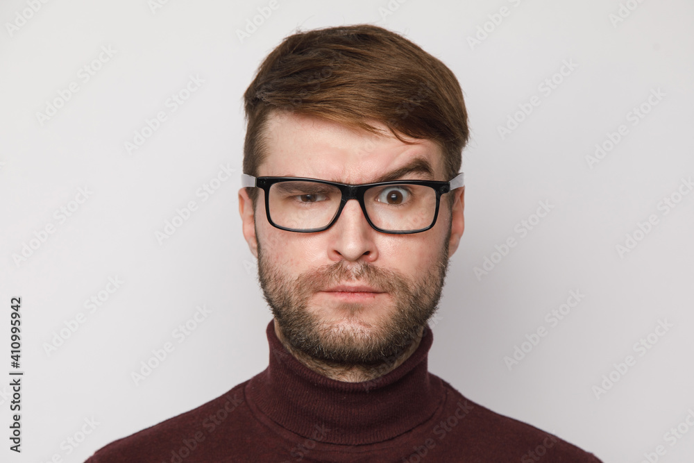 studio portrait of a frowning guy on a light background