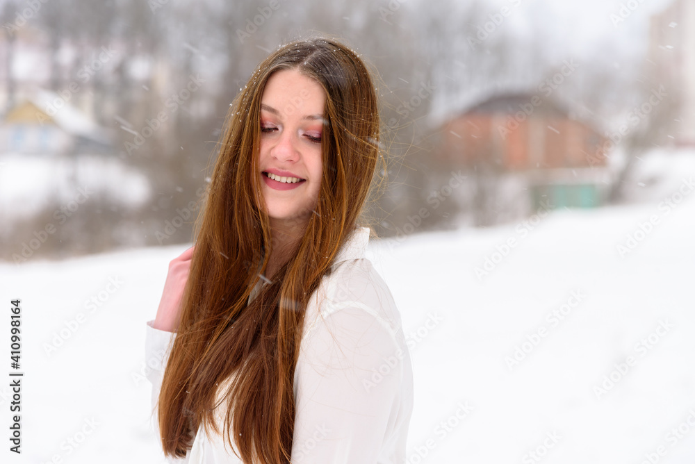 Beautiful young girl with long hair in the winter outdoors. Winter landscape background. Beautiful young girl with long hair in the winter outdoors. Winter landscape background.
