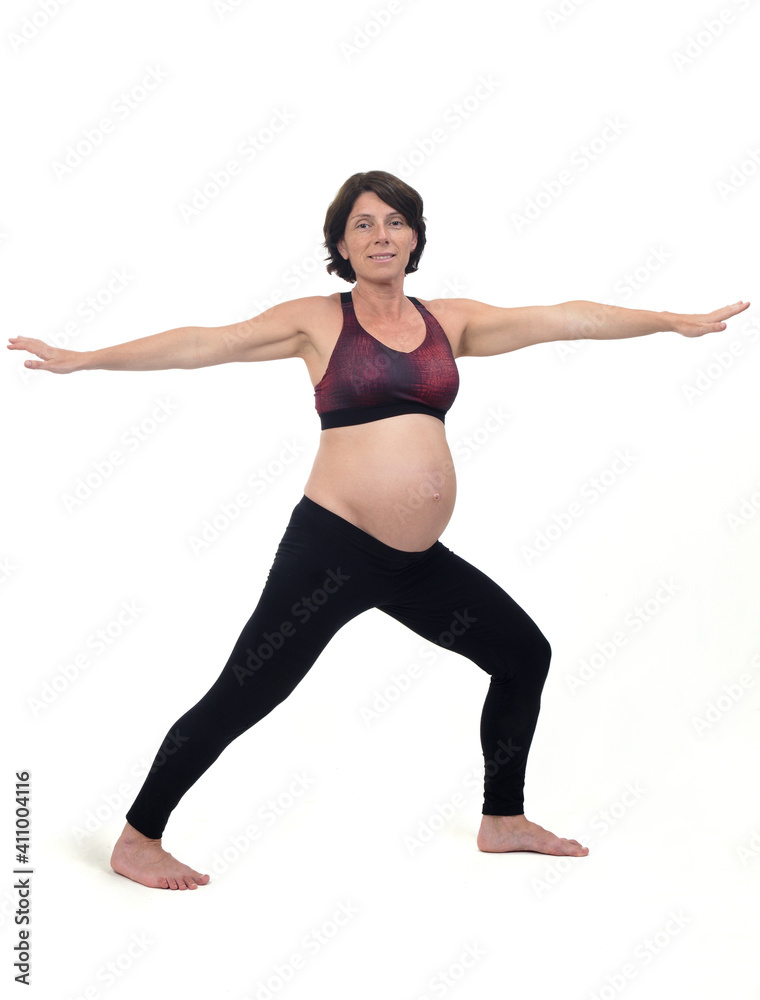  view of a pregnant woman doing standing exercises on white background, warrior pose