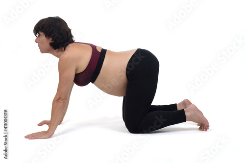 pregnant woman doing floor exercises on white background, cat pose