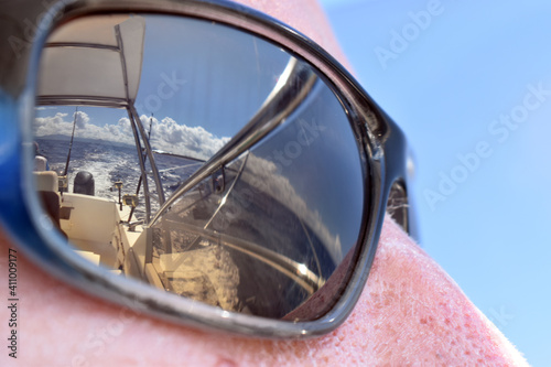 Close up of polarized sun glasses with the reflection of the back of a motor boat and some fishing equipment in a sunny day. 