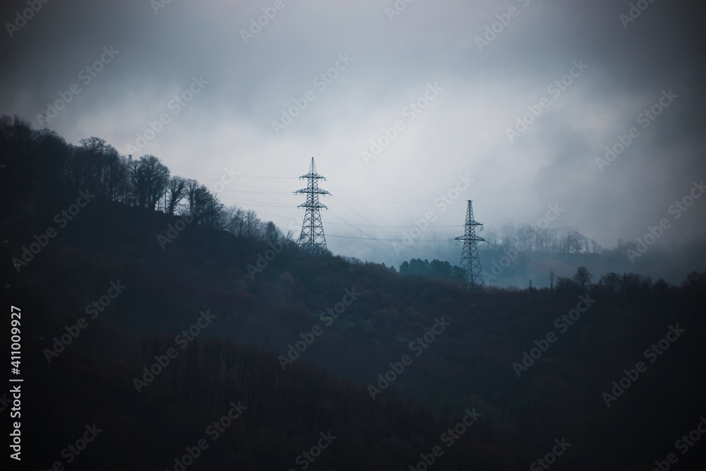 Fog in the evening in the mountains. Power lines. Dark mystical landscape.