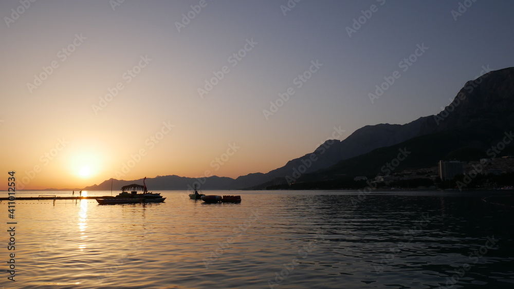 Beautiful sunset on the sea. Landscape at sea and mountains. The silhouette of boats near the pier during amazing sunset
