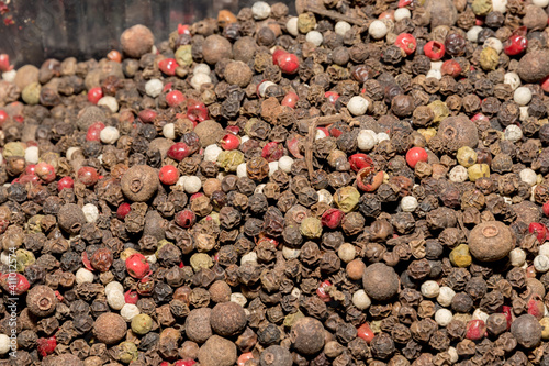 Mixture of dried round hot red pepper, black pepper, white pepper, green pepper as background