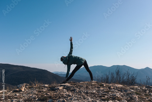 Girl in yoga pose on top of the mountain