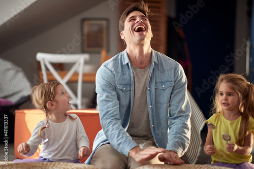 Obraz na plátně Dad and his daughters drumming on the furniture