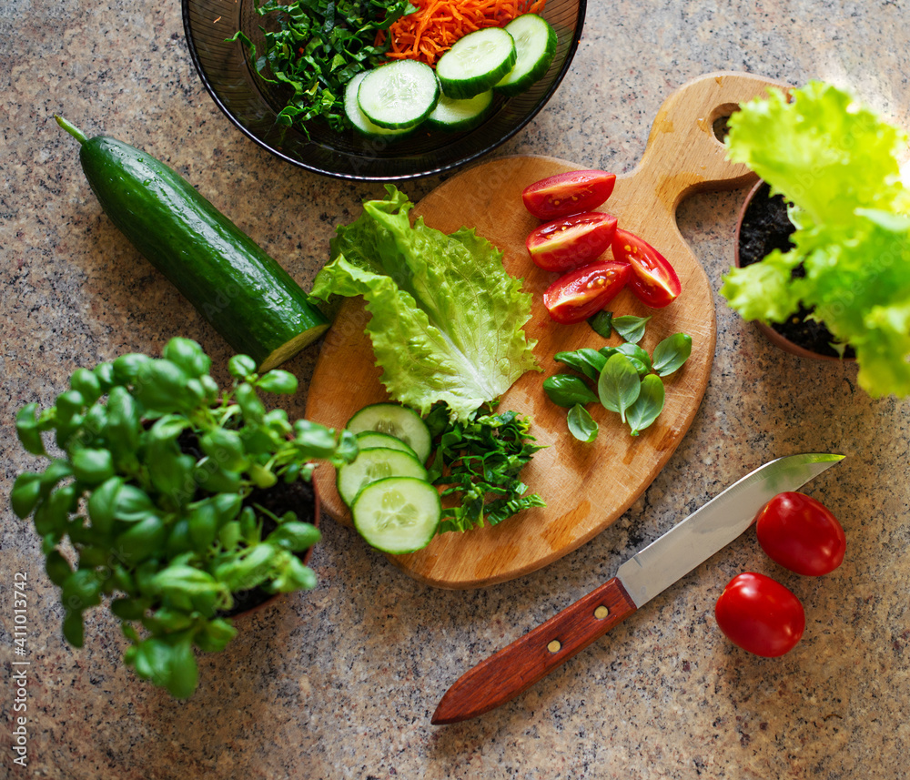 Slices of cucumber, tomatoes, spinach on a cutting board, ingredients for salad.