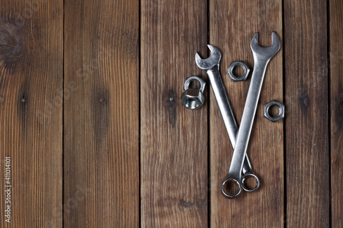 Spanners and screw-nuts on wooden plank background