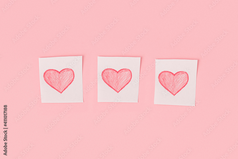 Three hearts drawn in pencil on pieces of white paper