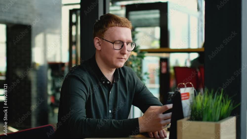 A man in a cafe looks at the phone. A man in a cafe looks at the phone.