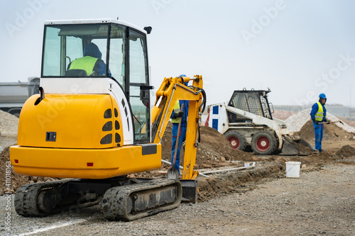 Two small excavators digging a trench on a construction site.