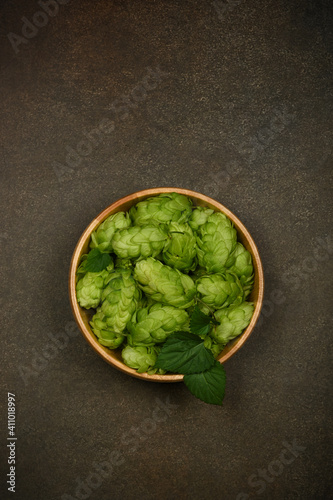 Wooden bowl of fresh green hops on table