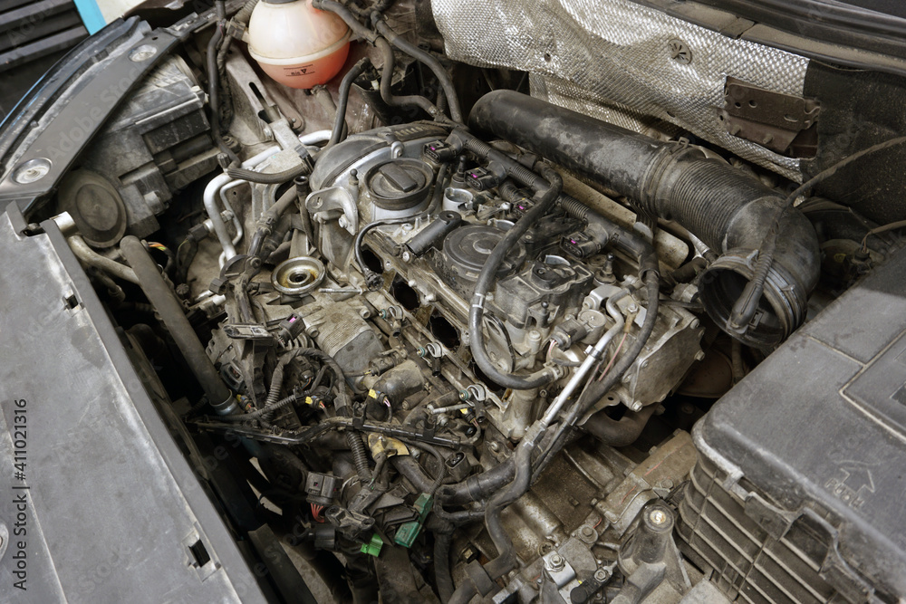 A partially disassembled engine of a modern car is ready for repair. The engine is dirty. Car service, spare parts. A partially disassembled engine of a modern car is ready for repair. The engine is dirty. Car service, spare parts.
