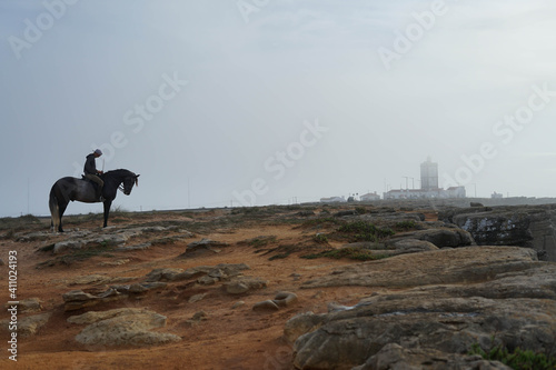 horse and rider next to lighthouse