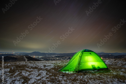 Tent in winter at night on a mountain top with a view of the village © onyx124