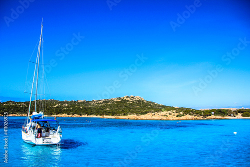 sailboat in the middle of the blue sea, lying on the rocks