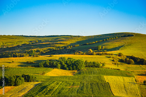 Green meadow with farmlands , natural landscape in the summer sunset near Tatgu Mures. Romania