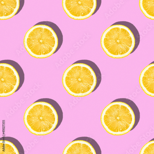Pattern made of lemon slices on pink background, tropical citrus fruit