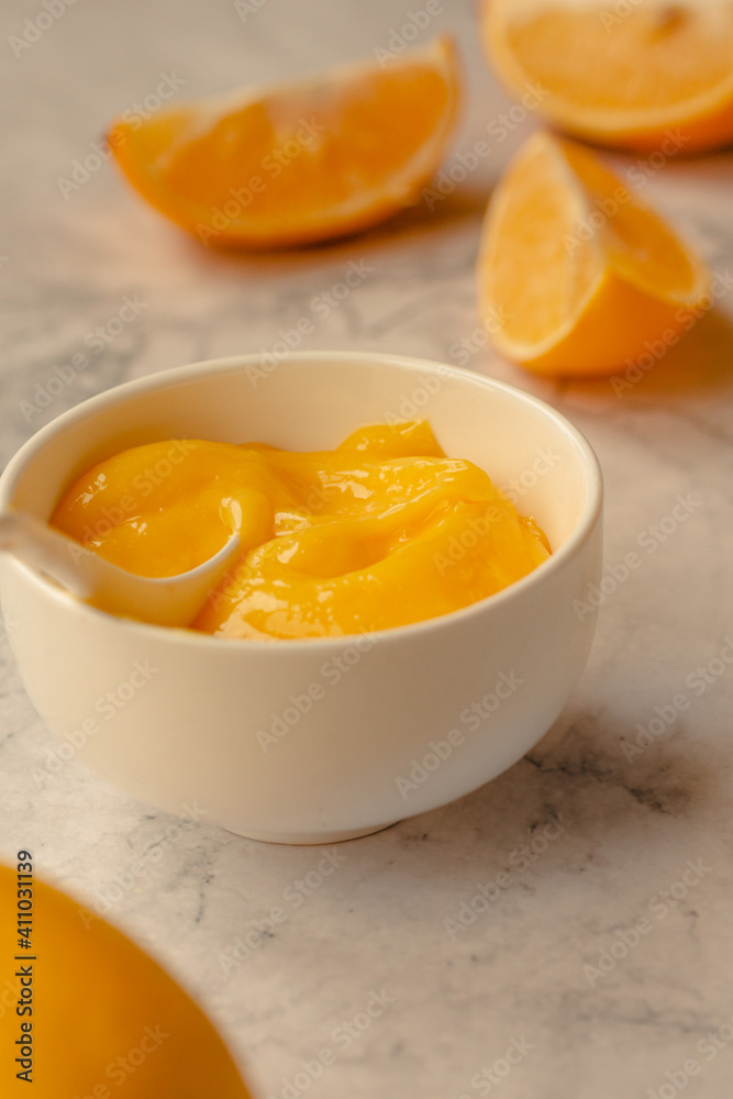 Composition with delicious Yellow lemons and Lemon curd in a sausepan white bowl on marble background Composition with delicious Yellow lemons and Lemon curd in a sausepan white bowl on marble background