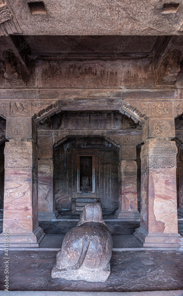 Badami, Karnataka, India - November 7, 2013: Cave temples above Agasthya Lake. Nandi statue in front of sanctum with Shivalingam. Heavy brown stone pillars and beams.