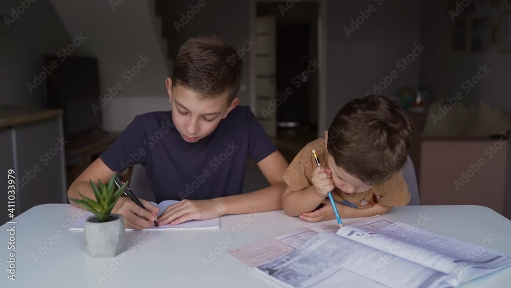 A schoolboy is learning lessons at home and his little brother is sitting next to him, the kid interferes with teaching lessons, learning at home
A schoolboy is learning lessons at home and his little brother is sitting next to him, the kid interferes with teaching lessons, learning at home