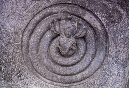 Badami, Karnataka, India - November 7, 2013: Cave temples above Agasthya Lake. Gray stone damaged sculpture on ceiling depicting Shiva surrounded by 5-headed snake. photo