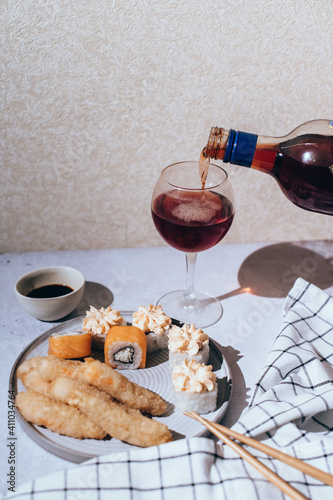 Fototapeta Naklejka Na Ścianę i Meble -  Pouring of red wine into glass and sushi set