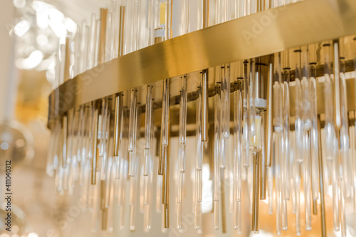 A luxury classic style chandelier is installed on the ceiling. The metal frame is a yellow gold color. Concept of interior decoration. Inside. Close up.