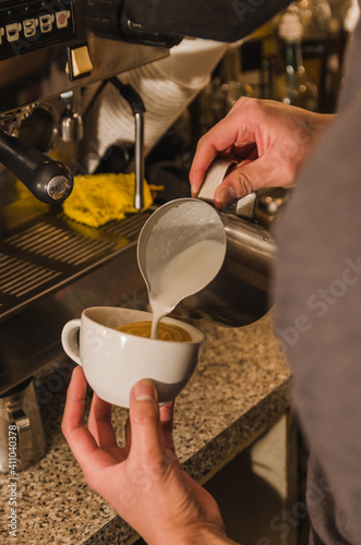 Barista boy preparing a coffee-based drink in a cafeteria, wearing black masks. 2