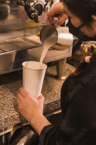 Barista girl preparing a coffee-based drink in a cafeteria  wearing black masks.  6