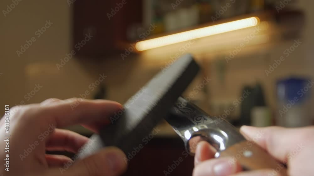 Hands sharpens hunting knife grindstone closeup