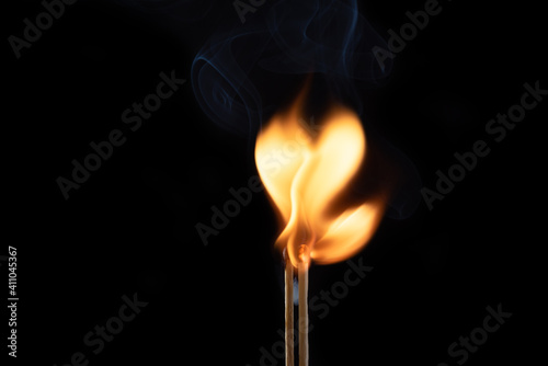 Two flaming matches with smoke and fire in the form of a heart