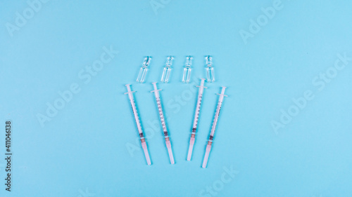 Syringes and ampoules for a vaccine on a light blue background. Concept of medicine  covid vaccination  health protection and life saving. Copy space.