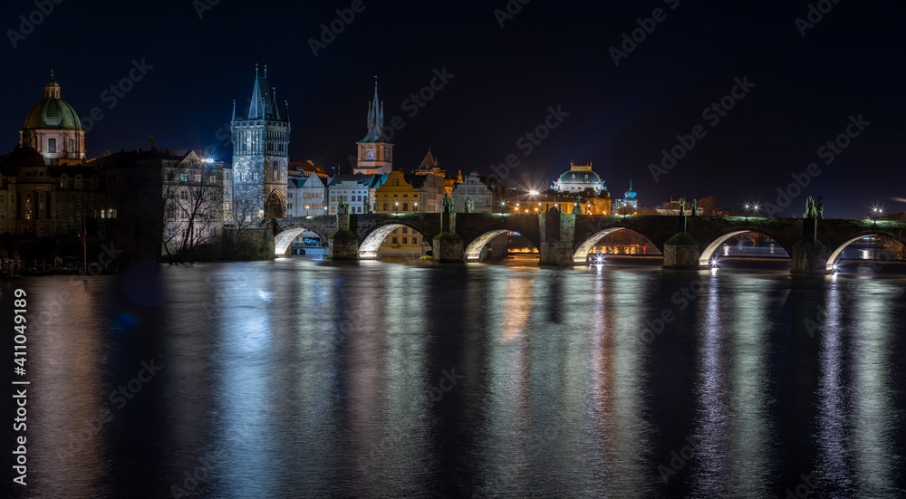 .illuminated Charles Bridge on the Vltava River and light from street lighting is reflected on the surface in the center of Prague at night