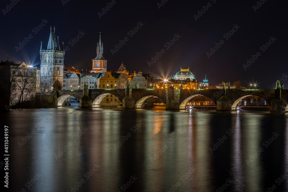 Fototapeta premium .illuminated Charles Bridge on the Vltava River and light from street lighting is reflected on the surface in the center of Prague at night