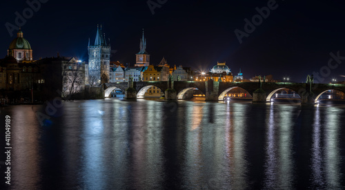 .illuminated Charles Bridge on the Vltava River and light from street lighting is reflected on the surface in the center of Prague at night