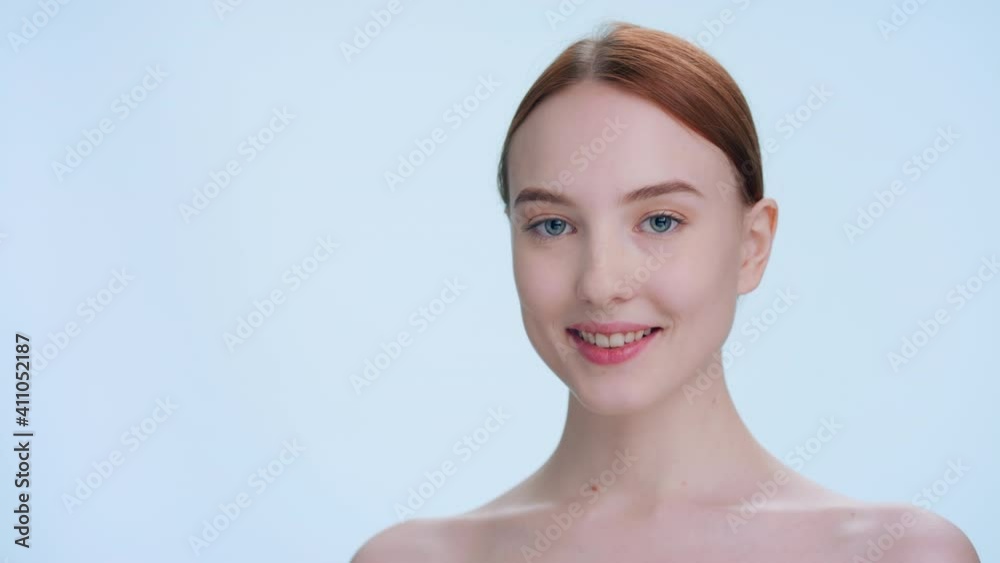 Close-up beauty portrait with place for product or sign. Young attractive ginger woman with perfect skin turns, looks at camera and smiles | skin care products commercial concept Close-up beauty portrait with place for product or sign. Young attractive ginger woman with perfect skin turns, looks at camera and smiles | skin care products commercial concept