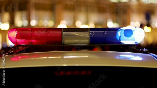Emergency vehicle lighting - police car roof mounted rotating light - red and blue. Night city scene.