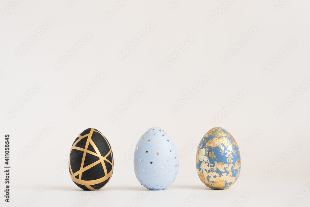 Three Easter golden decorated eggs on white background. Minimal easter concept. Happy Easter card with copy space for text. Top view, flatlay. Three Easter golden decorated eggs on white background. Minimal easter concept. Happy Easter card with copy space for text. Top view, flatlay.